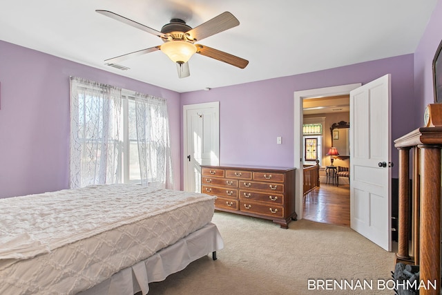 bedroom featuring light carpet, visible vents, and a ceiling fan