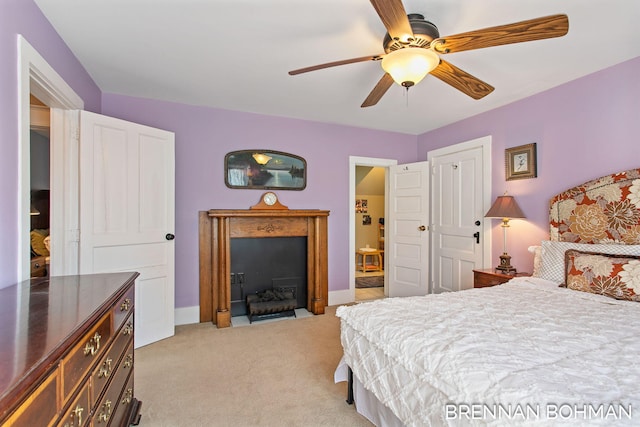 bedroom with a ceiling fan, a fireplace with flush hearth, light colored carpet, and baseboards