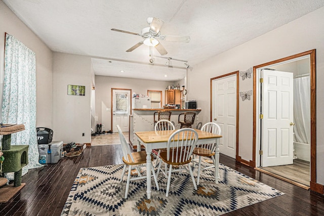 dining space featuring hardwood / wood-style flooring, a ceiling fan, baseboards, and a textured ceiling