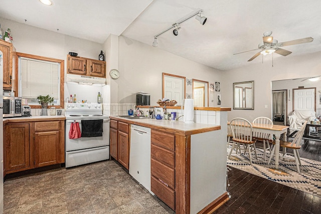 kitchen with white appliances, brown cabinetry, a peninsula, light countertops, and under cabinet range hood