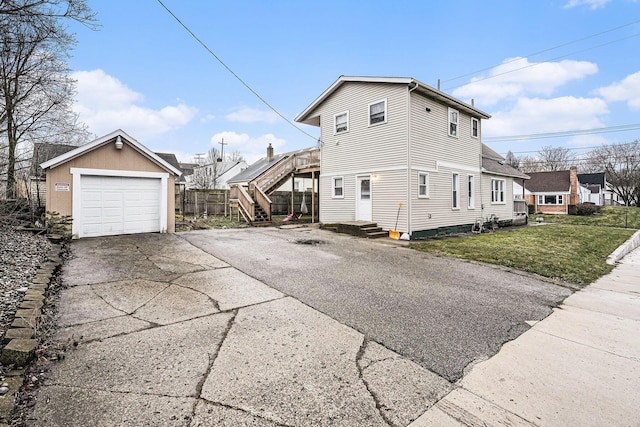 view of side of home featuring a detached garage, a lawn, and aphalt driveway