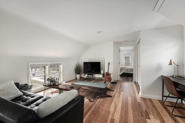 living room featuring a wealth of natural light, baseboards, light wood-type flooring, and lofted ceiling