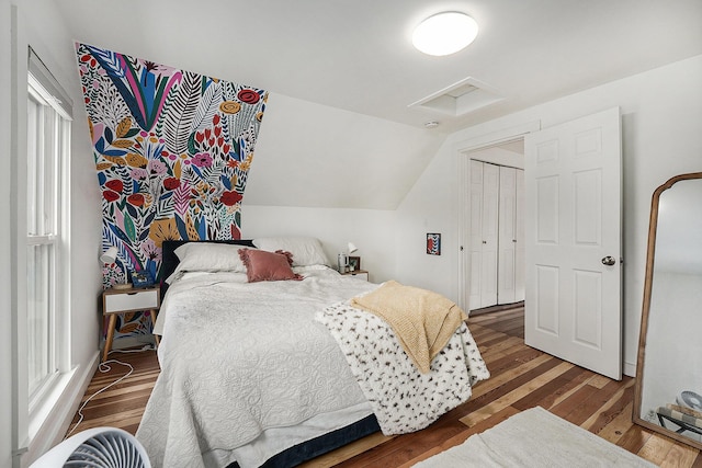 bedroom featuring vaulted ceiling, attic access, and wood finished floors