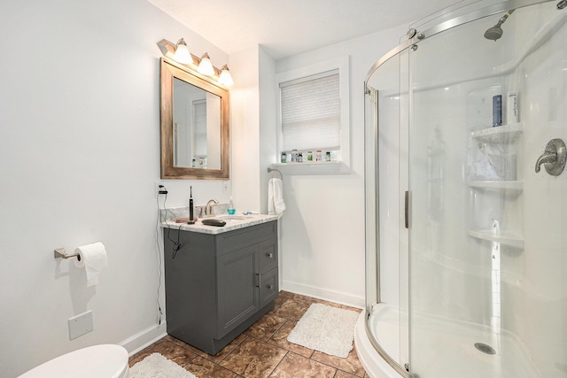 full bath featuring vanity, toilet, baseboards, and a stall shower