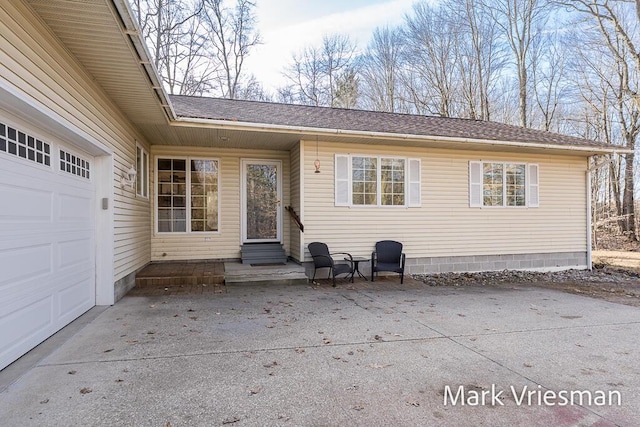 exterior space with a garage, a shingled roof, and entry steps