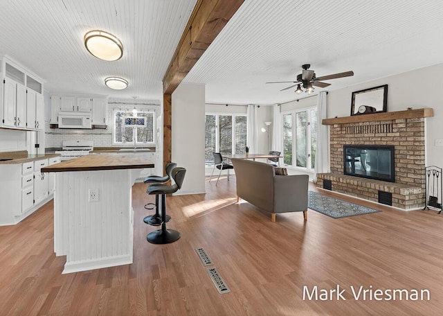 kitchen with wood counters, white appliances, open floor plan, and white cabinetry