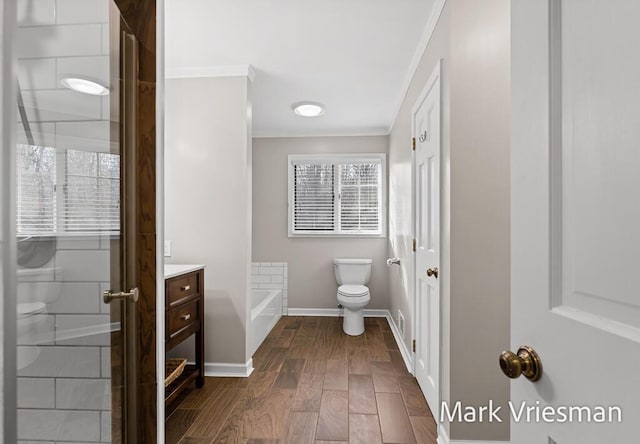 full bath featuring toilet, a washtub, wood finished floors, crown molding, and baseboards