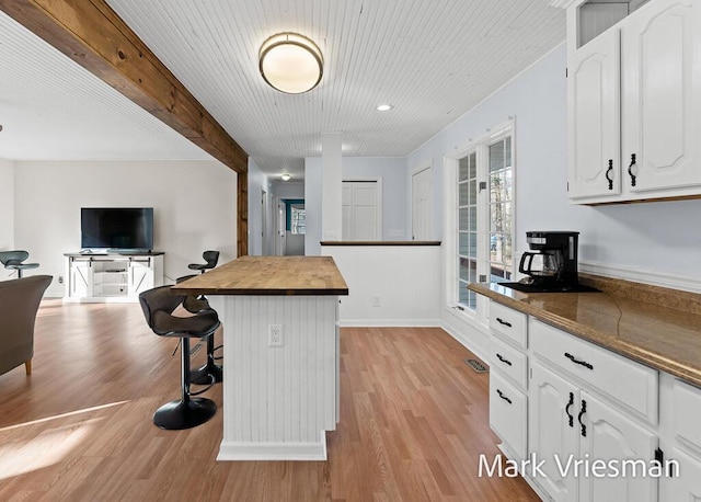 kitchen featuring white cabinetry, a breakfast bar, wood counters, and light wood-style floors