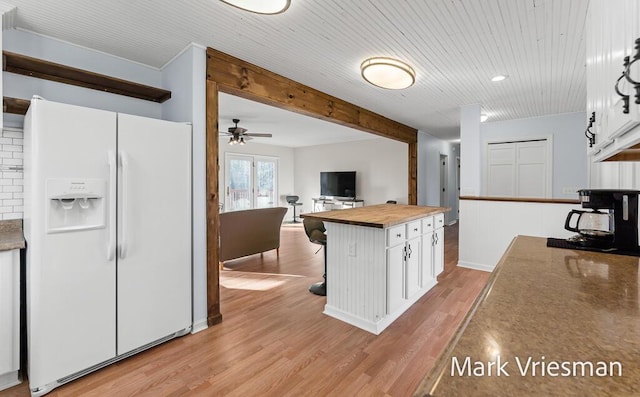 kitchen featuring beam ceiling, light wood-style flooring, butcher block countertops, white fridge with ice dispenser, and white cabinetry