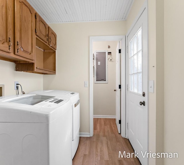 laundry room with baseboards, light wood finished floors, electric panel, separate washer and dryer, and cabinet space