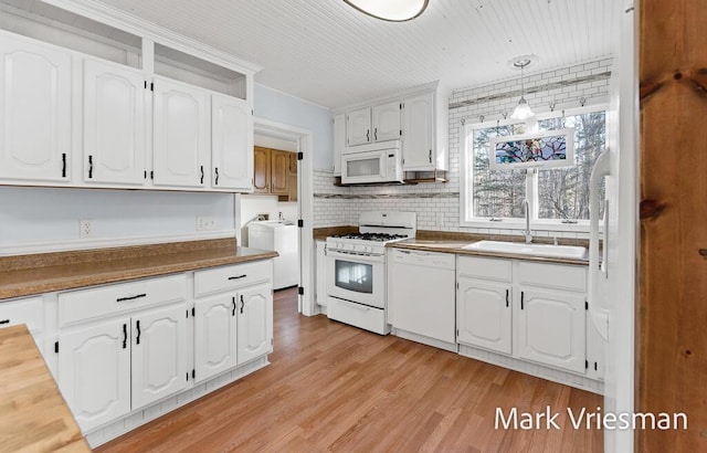 kitchen with light wood-type flooring, white cabinets, white appliances, washer / clothes dryer, and a sink