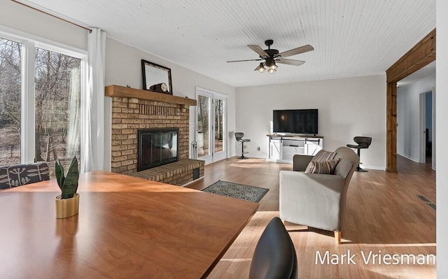 living room featuring baseboards, a ceiling fan, wood finished floors, and a fireplace