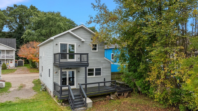 rear view of house featuring a balcony and dirt driveway