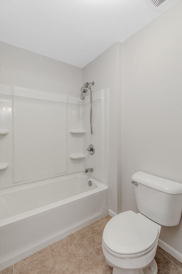 bathroom featuring tile patterned floors, toilet, baseboards, and shower / bath combination