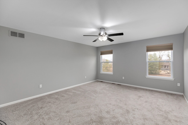 unfurnished room with a ceiling fan, baseboards, light colored carpet, and visible vents