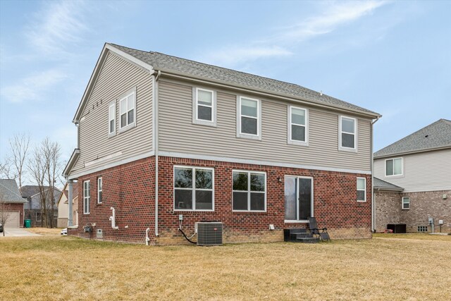 rear view of property featuring central air condition unit, entry steps, brick siding, and a yard