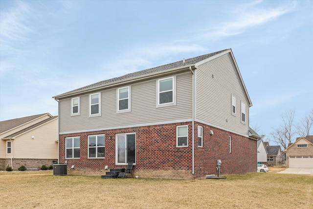 rear view of house featuring cooling unit, a garage, brick siding, and a yard