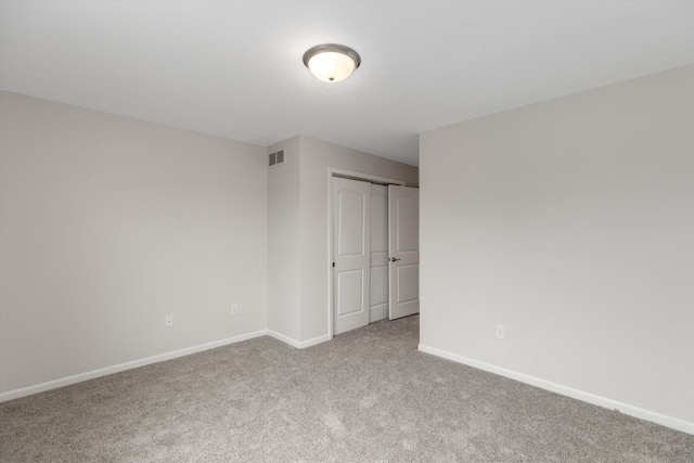 spare room with carpet flooring, baseboards, and visible vents