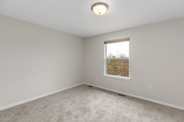 carpeted empty room featuring baseboards and visible vents