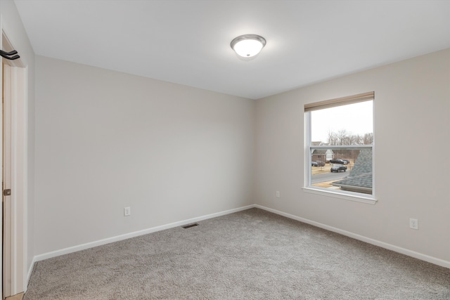 spare room featuring baseboards, visible vents, and carpet floors