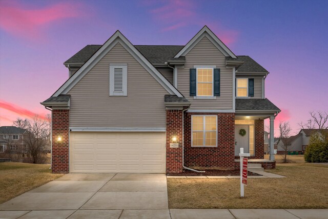 traditional home featuring driveway, brick siding, a garage, and a front lawn