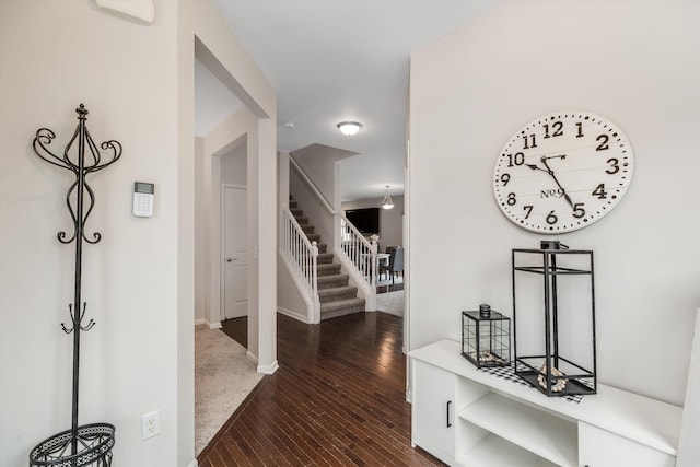 corridor featuring baseboards, stairs, and wood finished floors