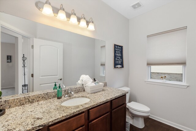 bathroom with visible vents, baseboards, toilet, wood finished floors, and vanity