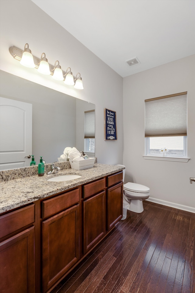 bathroom featuring vanity, wood-type flooring, toilet, baseboards, and visible vents