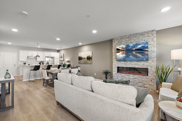 living area with light wood-style flooring, recessed lighting, and a fireplace