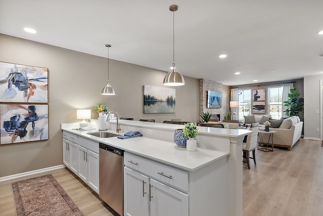 kitchen featuring a sink, light wood-style floors, a peninsula, light countertops, and dishwasher