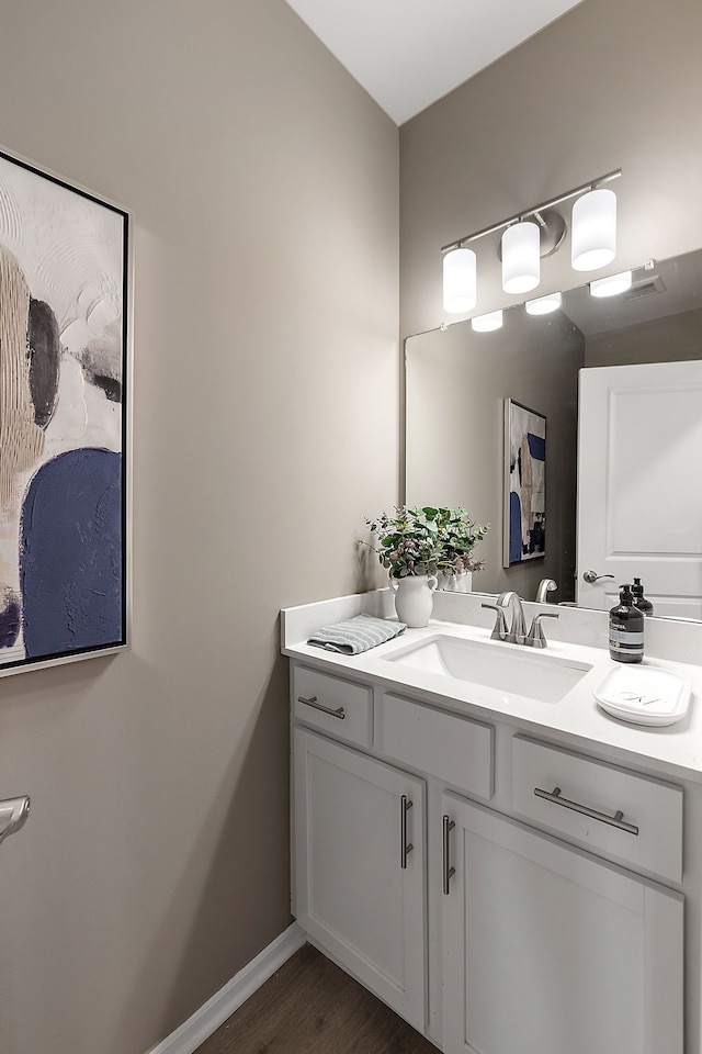 bathroom featuring vanity, wood finished floors, and baseboards