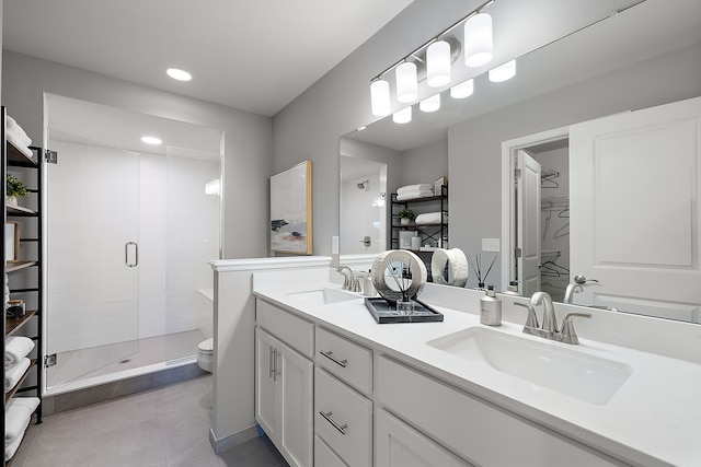 bathroom with double vanity, a stall shower, toilet, and a sink