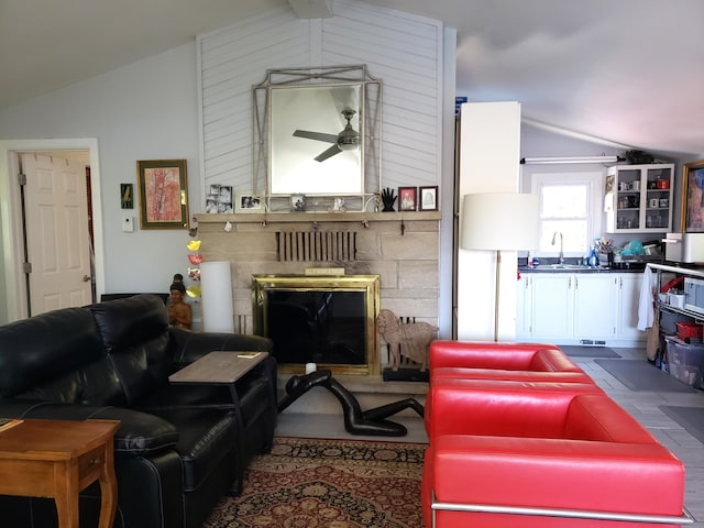 living room featuring a fireplace with raised hearth, a ceiling fan, and vaulted ceiling