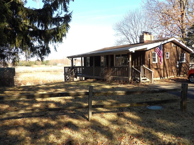 view of front facade featuring a porch, a chimney, and fence