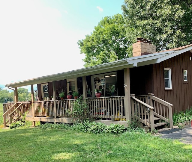 rear view of house with a lawn, board and batten siding, and a chimney