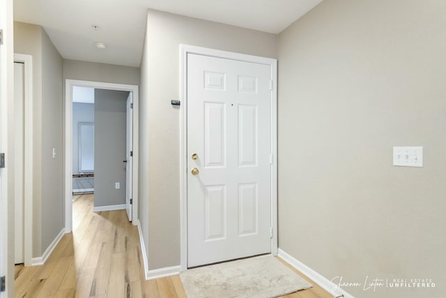 doorway featuring baseboards and light wood-style floors