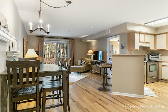 dining space featuring an inviting chandelier, light wood-style floors, visible vents, and baseboards