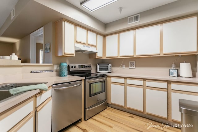 kitchen with visible vents, stainless steel appliances, light countertops, light wood-style floors, and under cabinet range hood