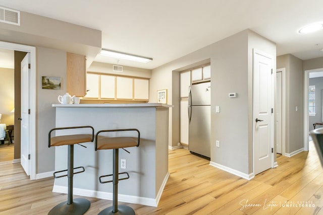 kitchen featuring light wood finished floors, visible vents, and freestanding refrigerator