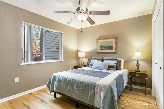 bedroom featuring baseboards, wood finished floors, and a ceiling fan