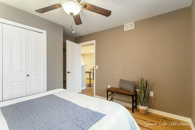 bedroom with visible vents, a ceiling fan, a closet, light wood finished floors, and baseboards