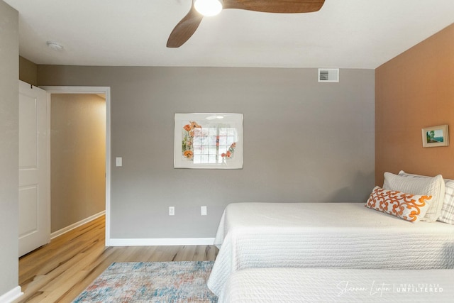 bedroom featuring ceiling fan, wood finished floors, visible vents, and baseboards