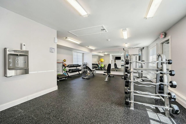 gym featuring baseboards and attic access