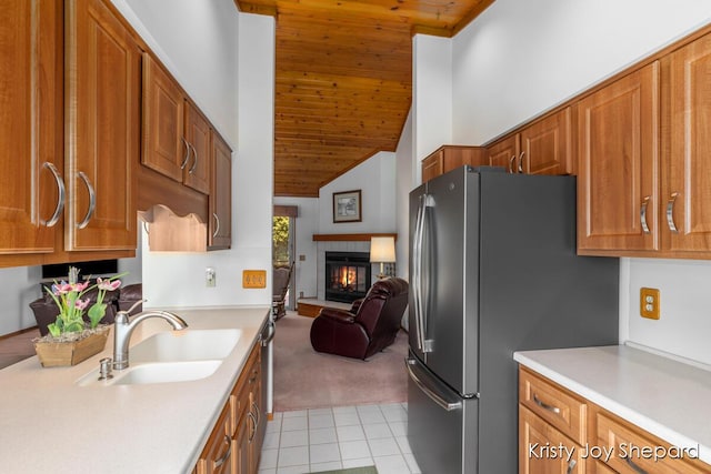 kitchen featuring a glass covered fireplace, light countertops, brown cabinets, and a sink