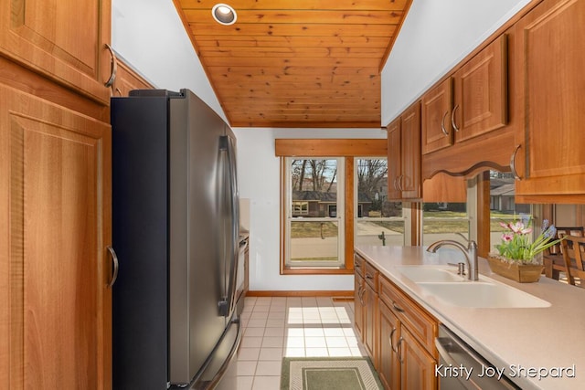 kitchen with light countertops, light tile patterned floors, brown cabinets, stainless steel appliances, and a sink