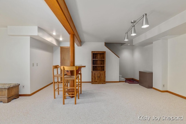 carpeted dining area featuring beam ceiling, rail lighting, stairs, and baseboards