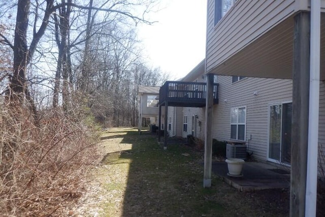 view of side of home featuring a yard, a balcony, and central AC