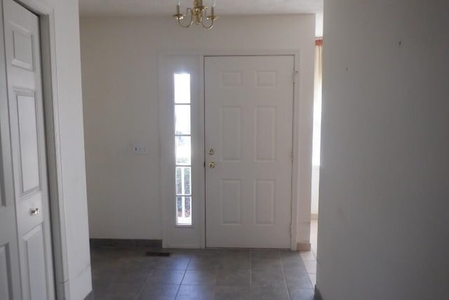 tiled foyer featuring visible vents, baseboards, and a chandelier