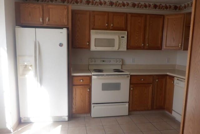 kitchen featuring light tile patterned floors, white appliances, brown cabinets, and light countertops