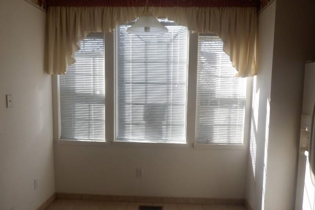 tiled empty room featuring baseboards